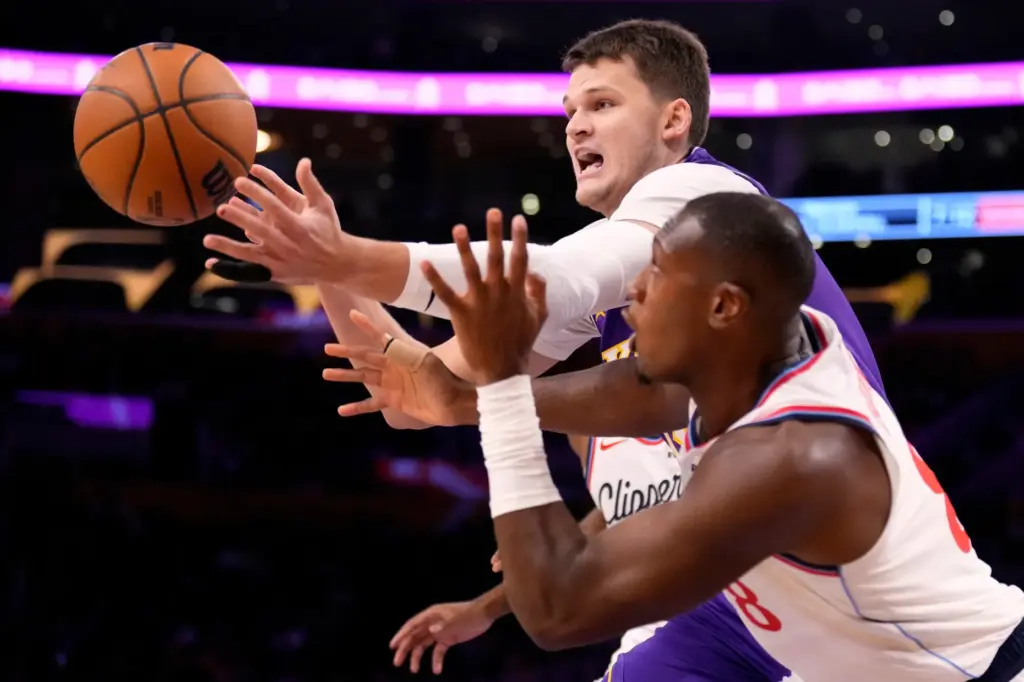 Lakers center Walker Kessler, top, and Clippers guard Kris Dunn...