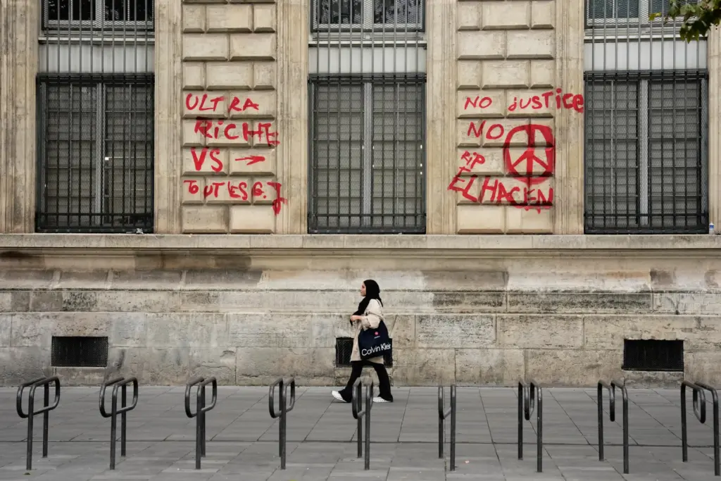 A woman walks past a building with graffiti in Paris.