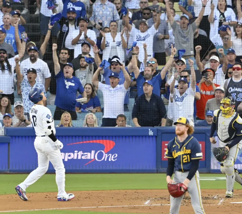 Dodgers star Shohei Ohtani, left, begins to celebrate after hitting...
