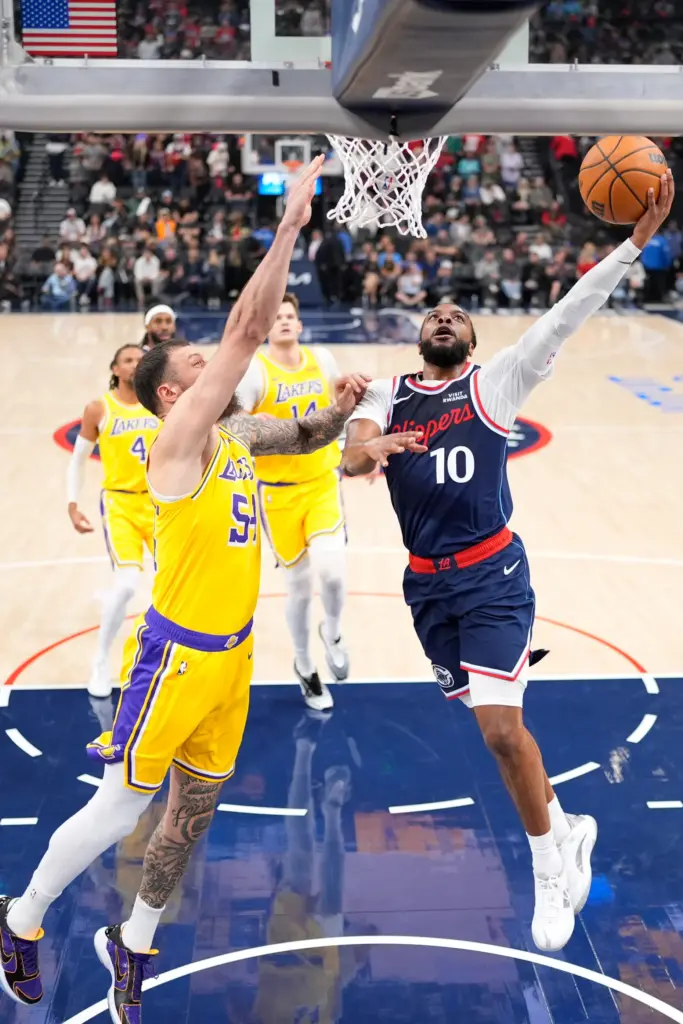 Clippers point guard Darius Garland, right, shoots as Lakers forward...