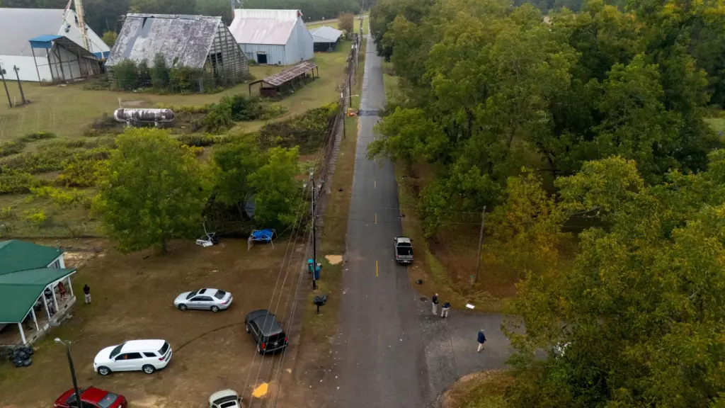 Authorities, below to the right, investigate the scene of a...