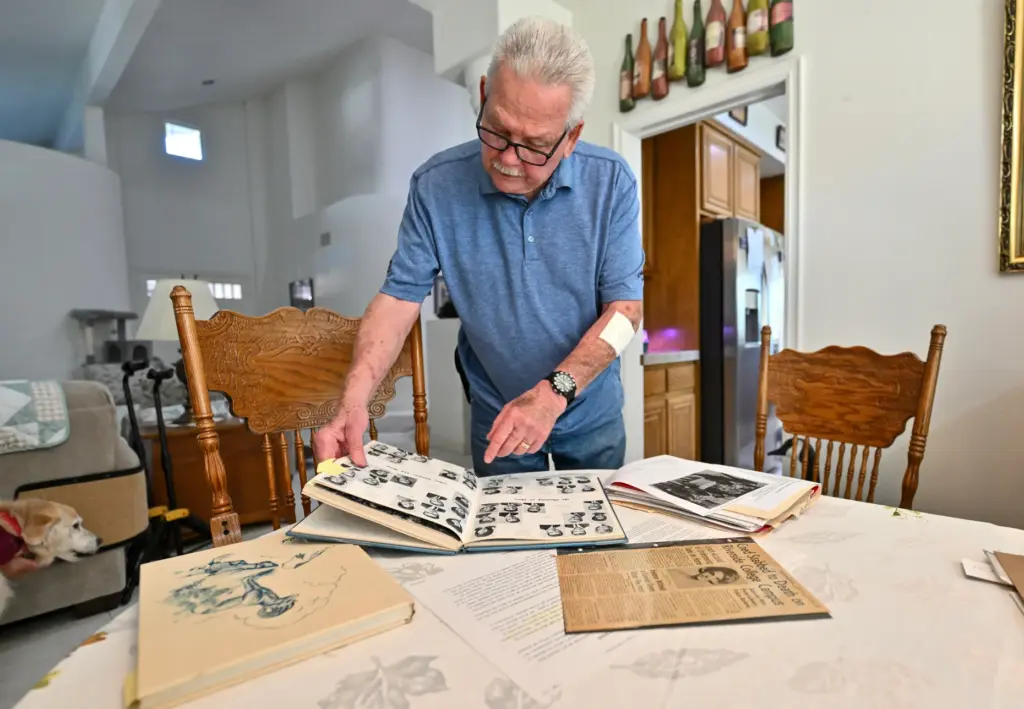 Ken Welty looks through a yearbook from high school with...