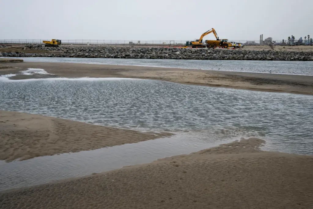 Heavy equipment scoops up loads of sand at the Santa...