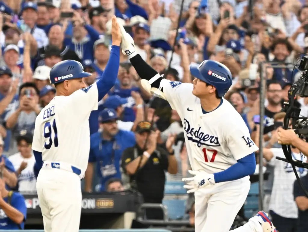 Dodgers star Shohei Ohtani, right, celebrates with third base coach...