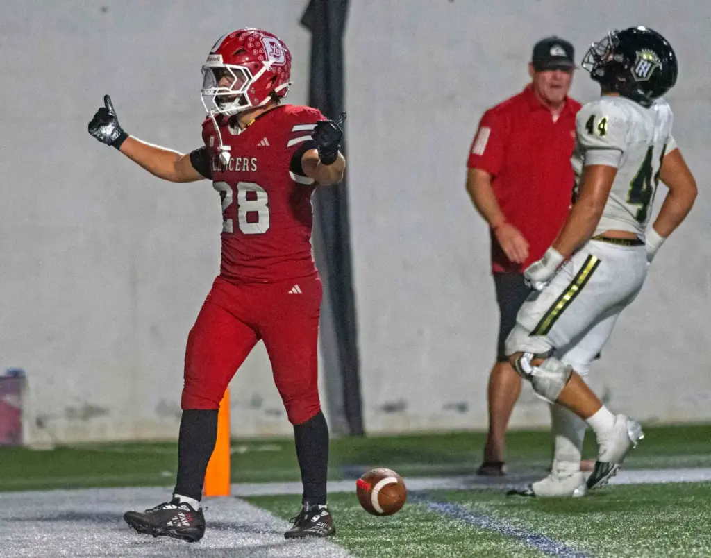 Orange Lutheran’s Ryan Christianson (28) celebrates another touchdown while Serviteâs...