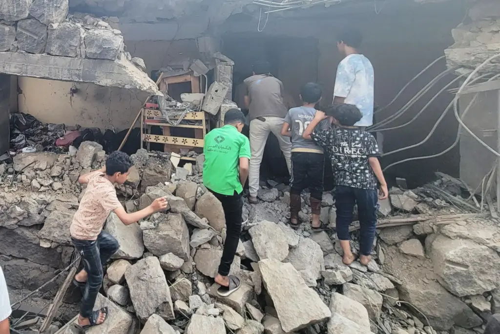 Residents walk amid debris from their homes after a missile strike in Seina, Taiz, Yemen.