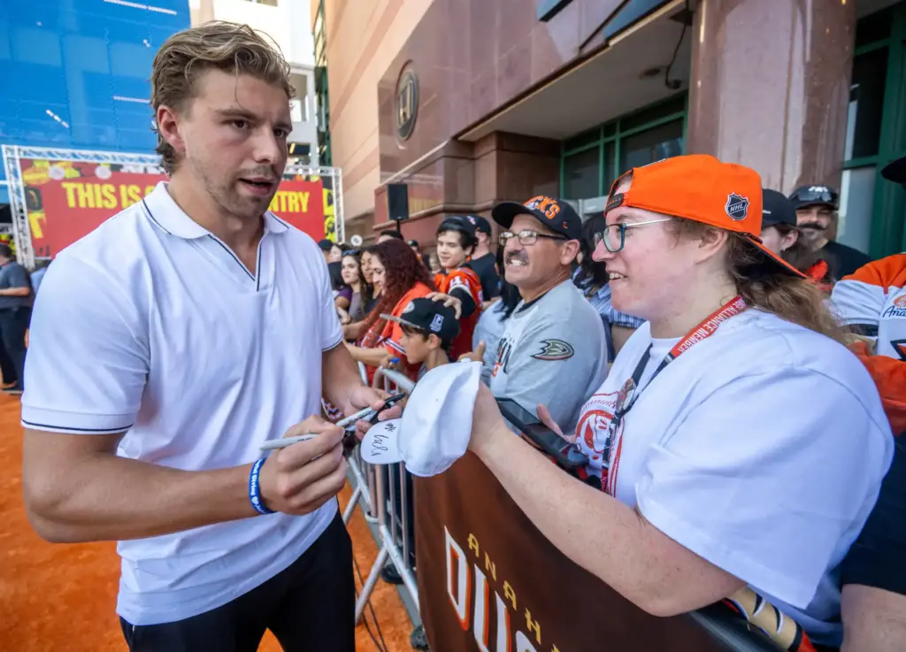 Ducks player Tristan Luneau signs autographs on the orange carpet...