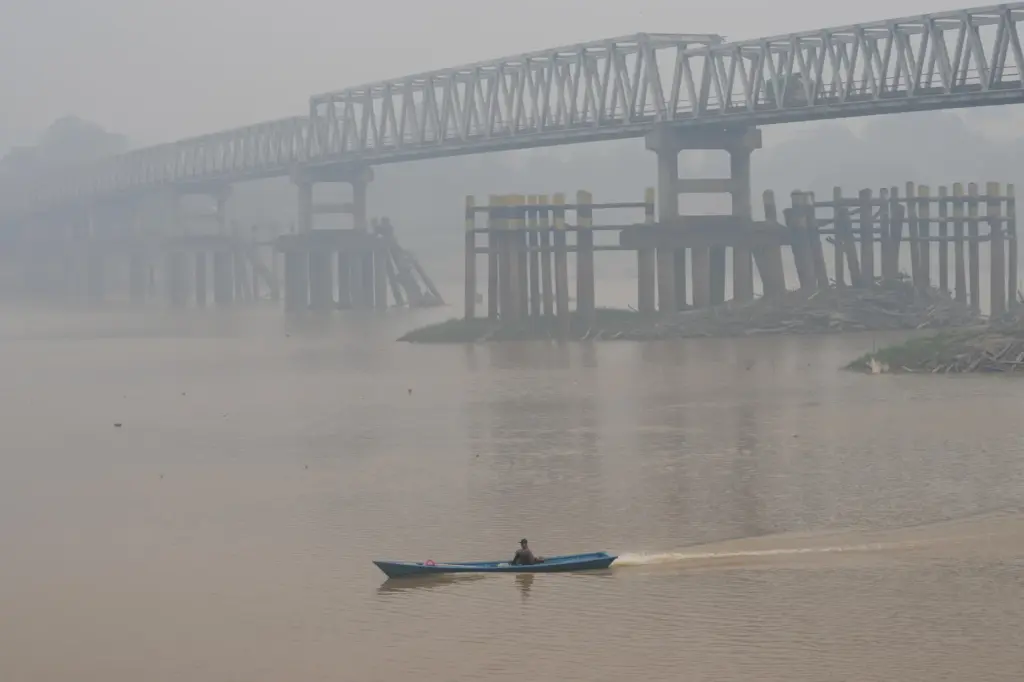 A man pilots a motorboat along the Kapuas River as...