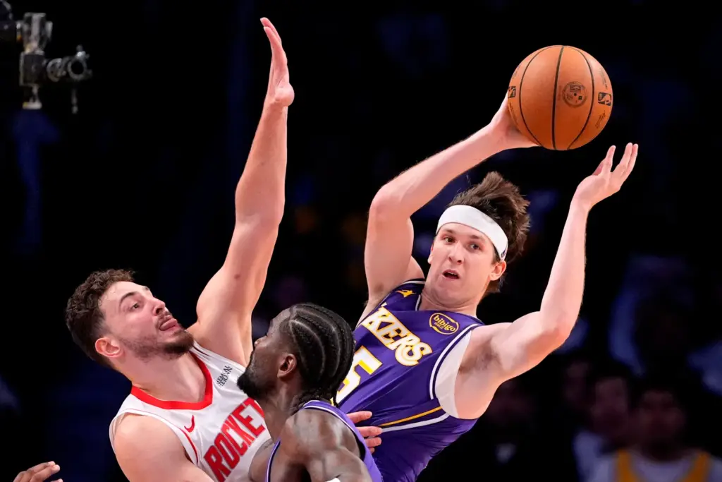 Lakers guard Austin Reaves, right, passes the ball while under...