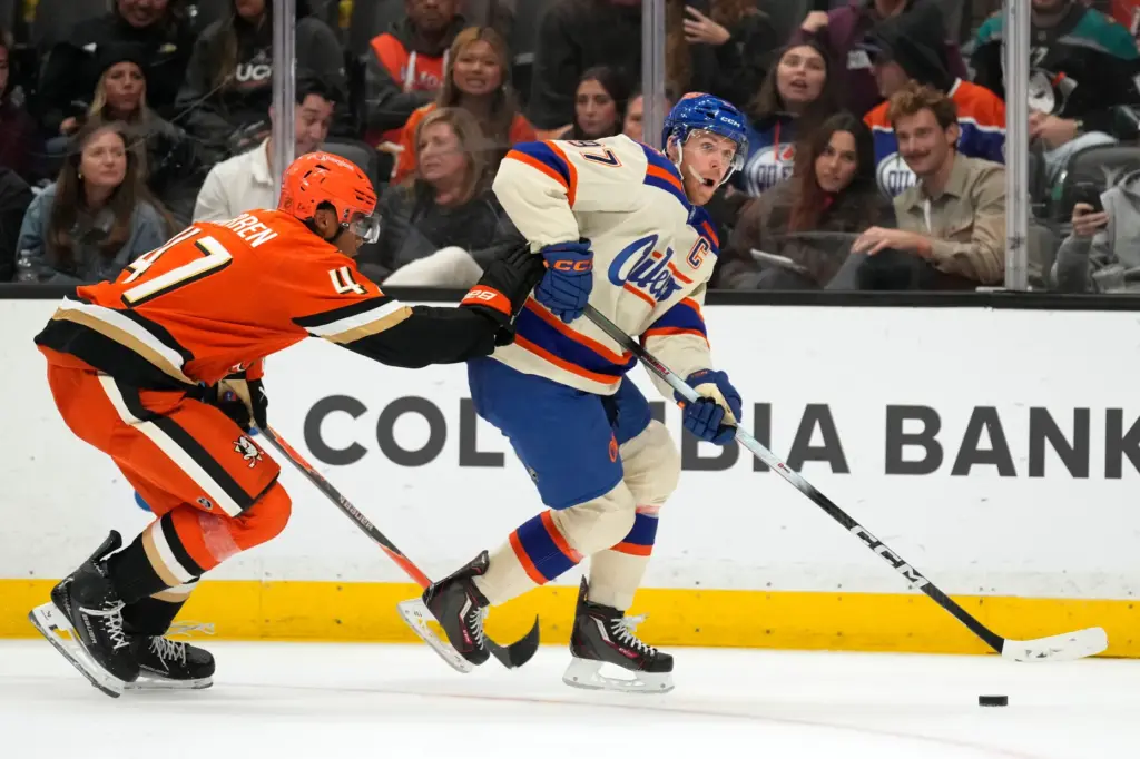 Edmonton Oilers center Connor McDavid, right, moves the puck up...