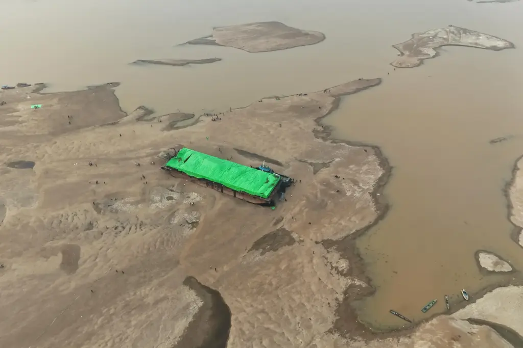 People surround a barge that is stranded on a dry...