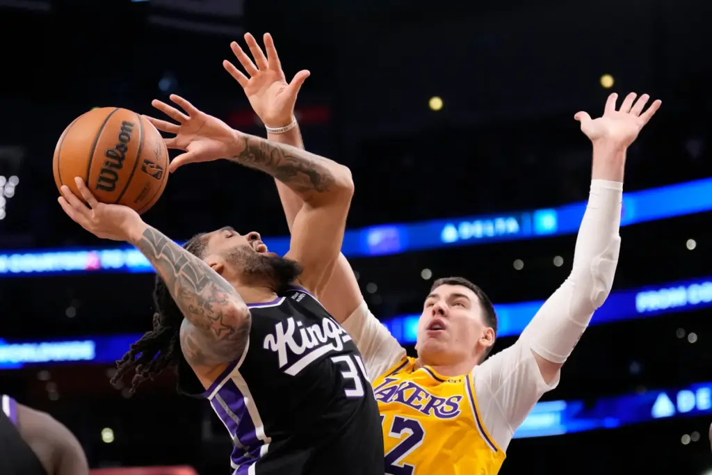 Sacramento Kings guard Emanuel Sharp, left, shoots as Lakers forward...