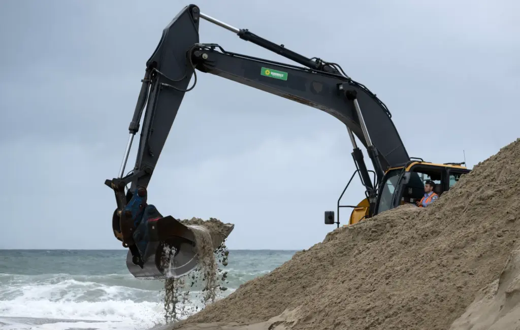 A backhoe is used to create sand berms at Main...