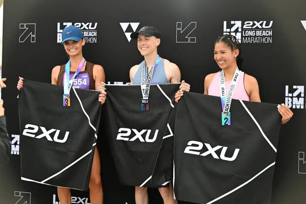 Jules Madzia, center, is the first female finisher of the...