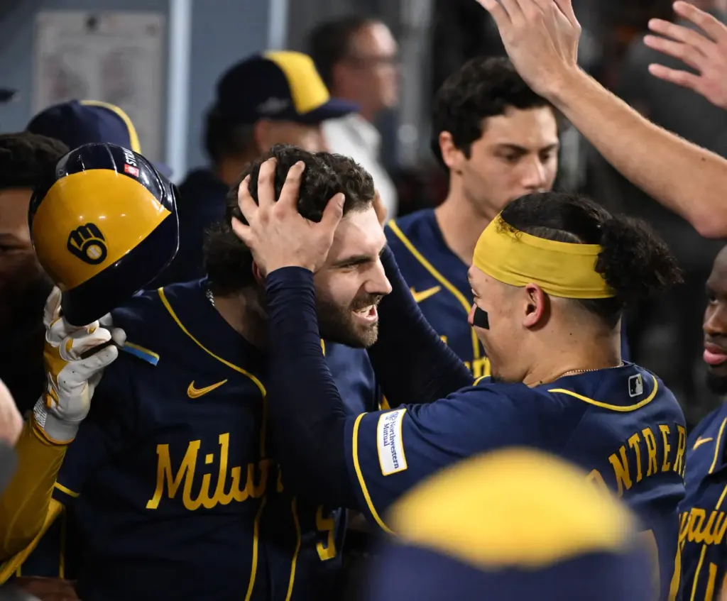 The Milwaukee Brewers’ Garrett Mitchell, left, celebrates in the dugout...