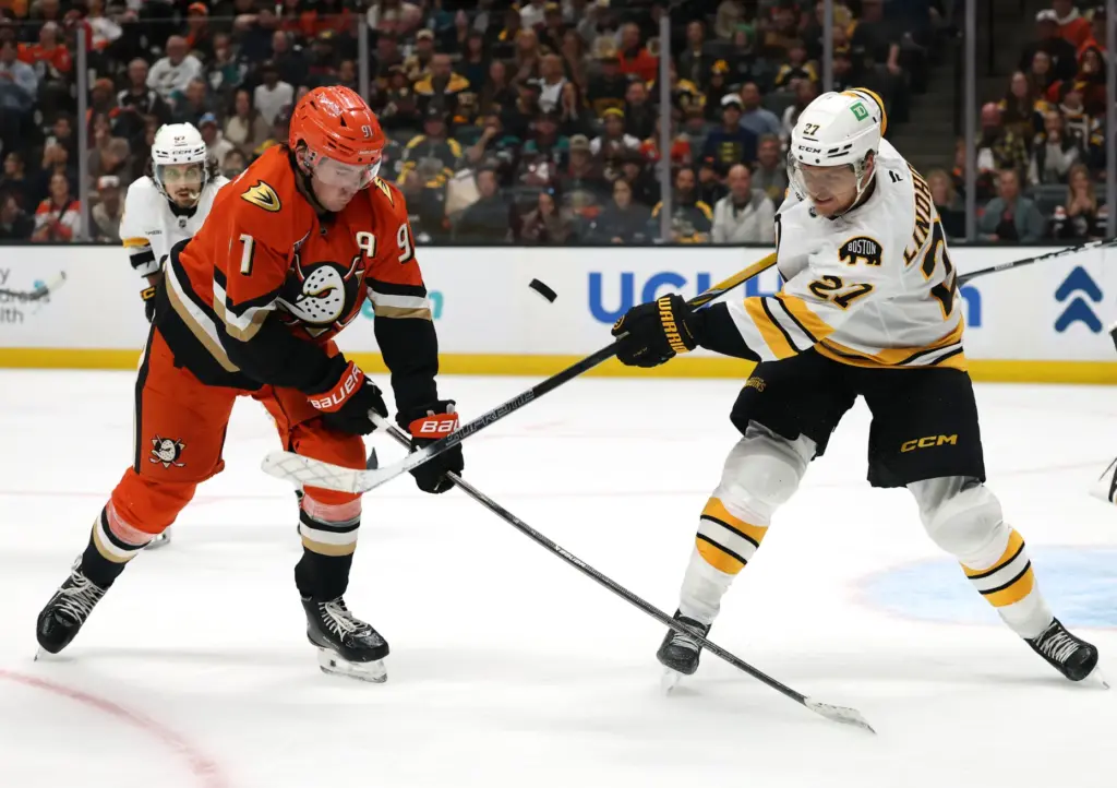 The Boston Bruins’ Hampus Lindholm, right, clears the puck in...