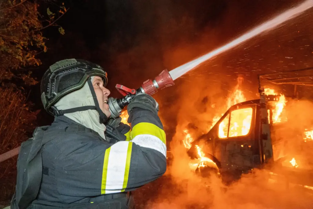 A rescue worker tries to put out a fire of...
