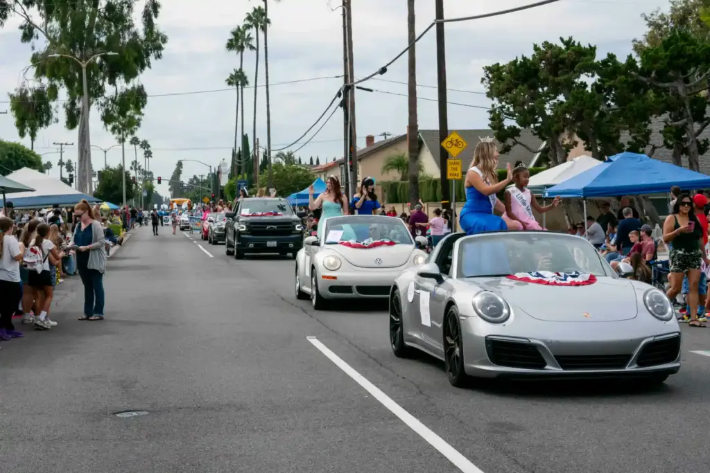 Cars bearing red white and blue decorations drive up N....