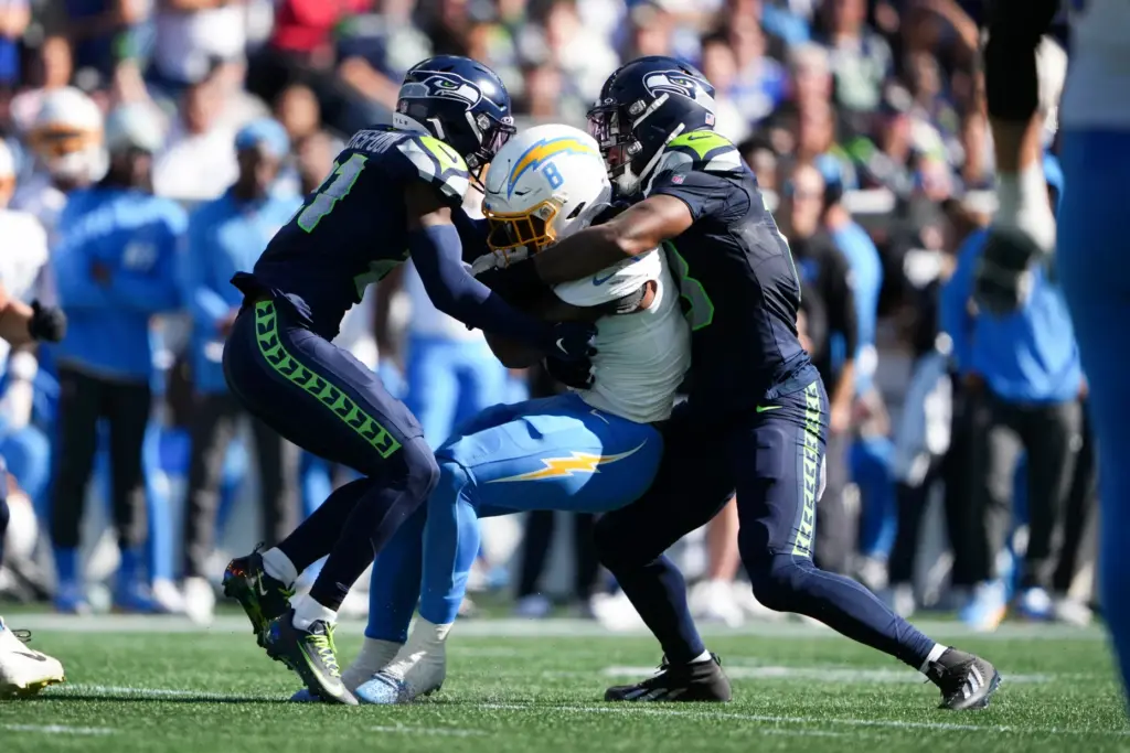 Chargers running back Omarion Hampton, center, is tackled by Seattle...