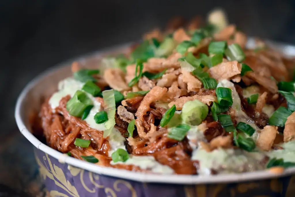 A Hawaiian bread base is topped with slow-cooked pulled pork,...