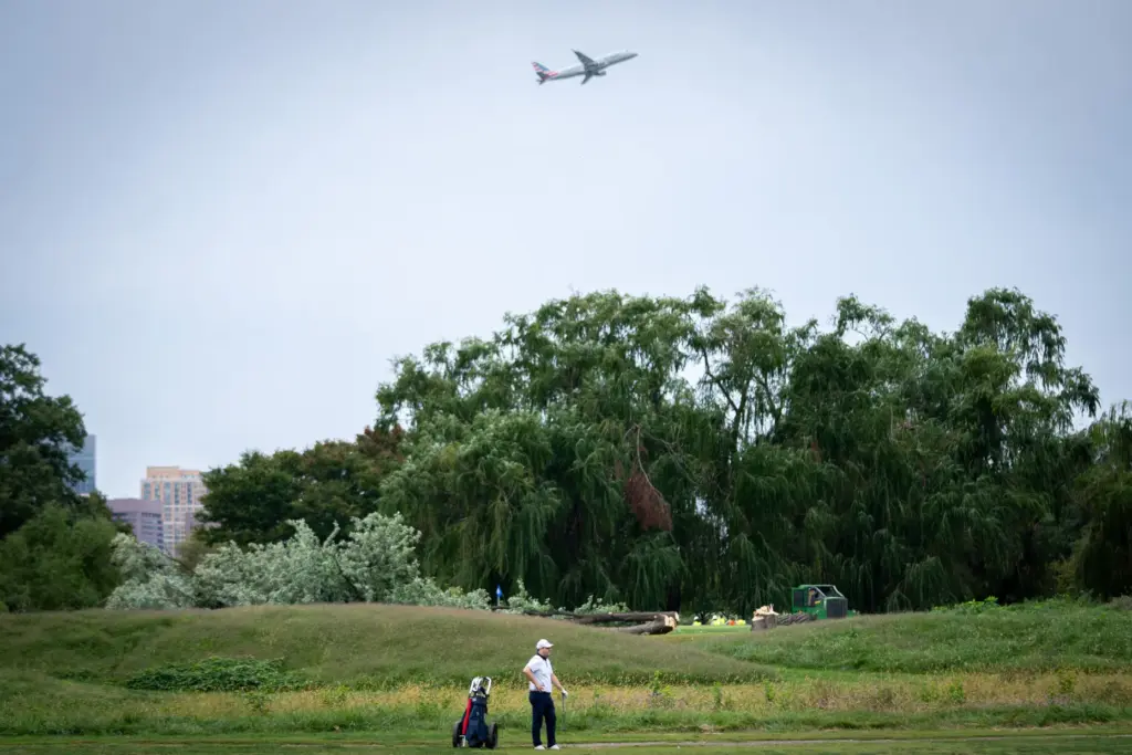 A golfer pauses near trees recently cut down by the...