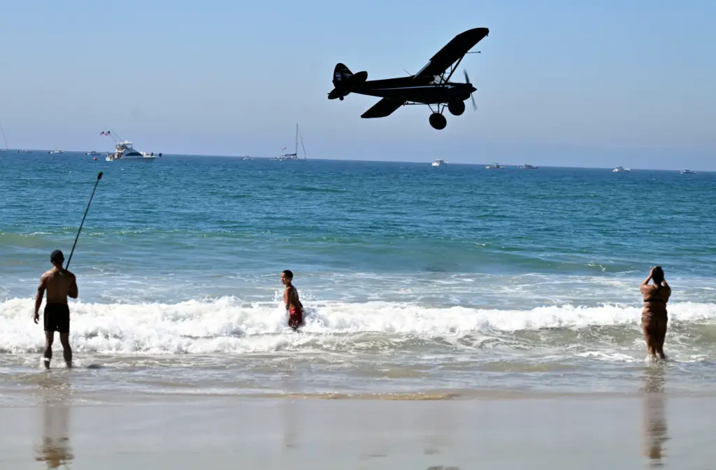 A low-flying aircraft flies along the shoreline in Huntington Beach....