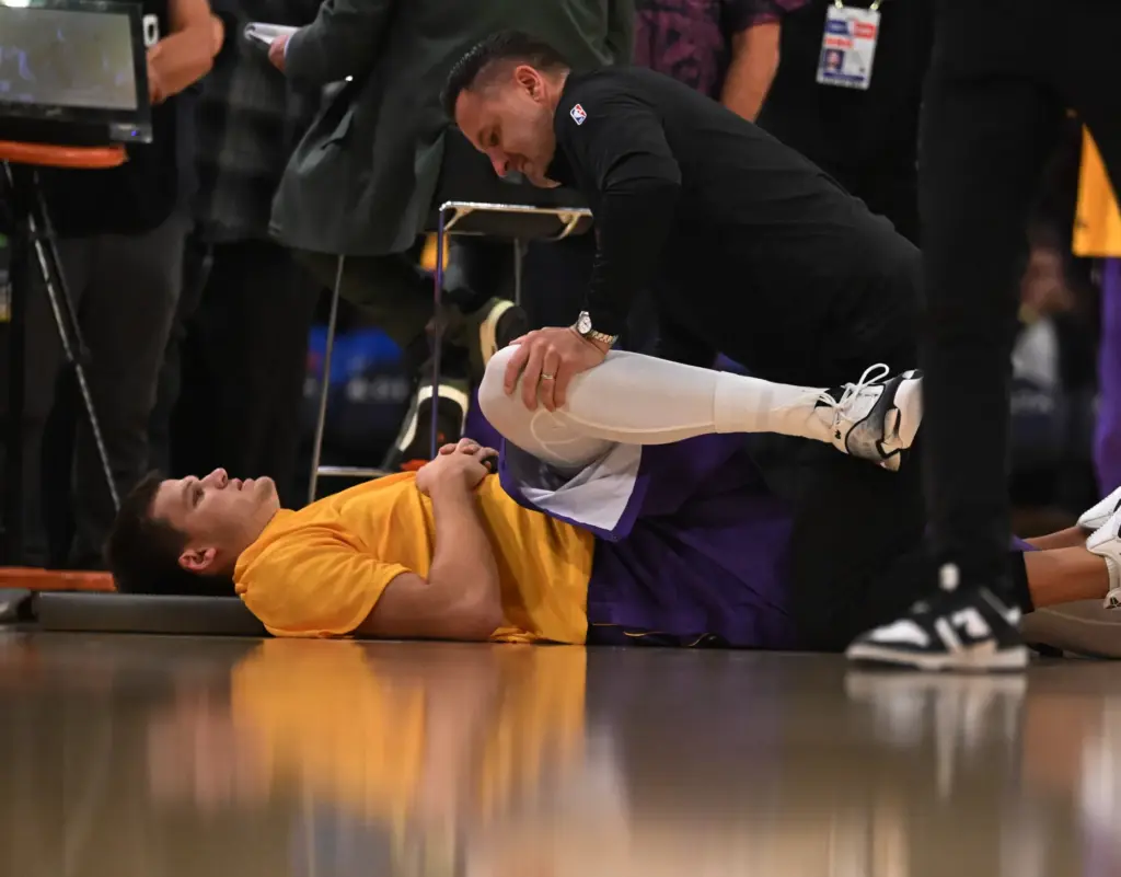 Lakers center Walker Kessler, left, stretches with the help of...