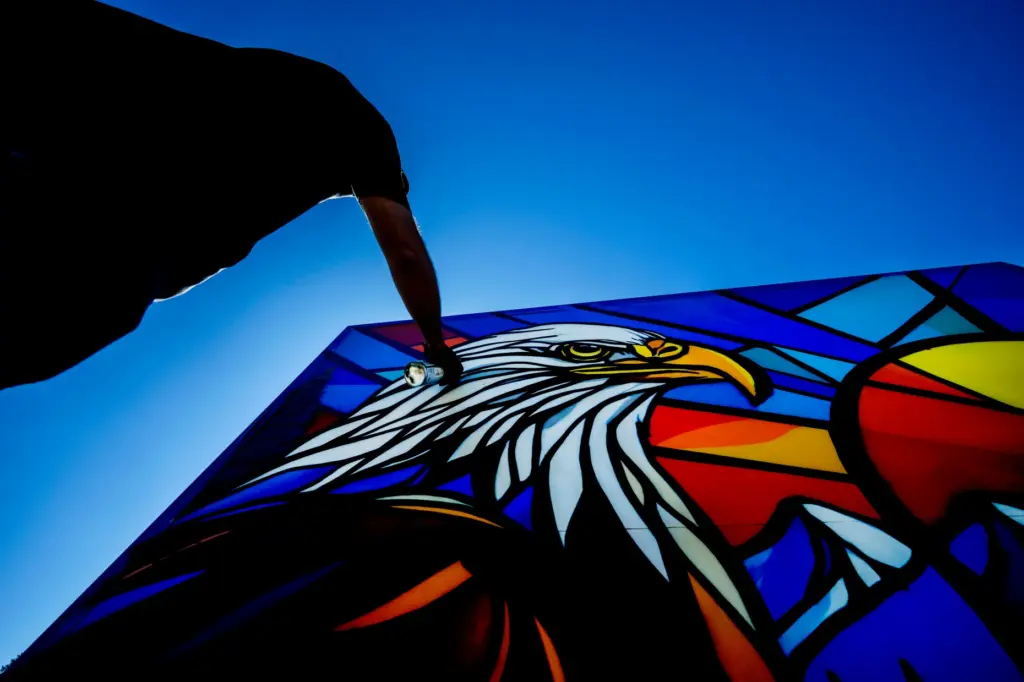 Artist Wes Abarca spray paints a mural of Bald Eagle...