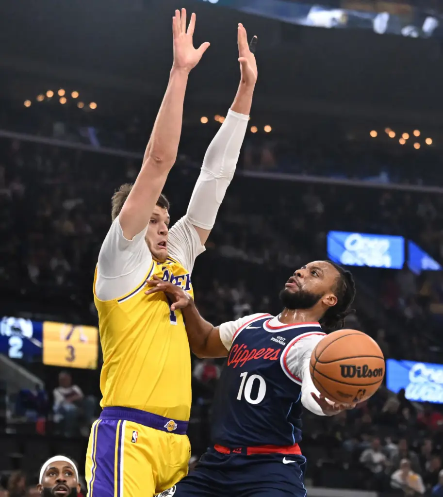 Clippers point guard Darius Garland, right, drives to the basket...