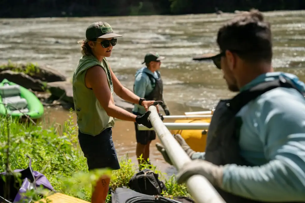Workers from MountainTrue clear IPEX PVC pipe from the riverbank...