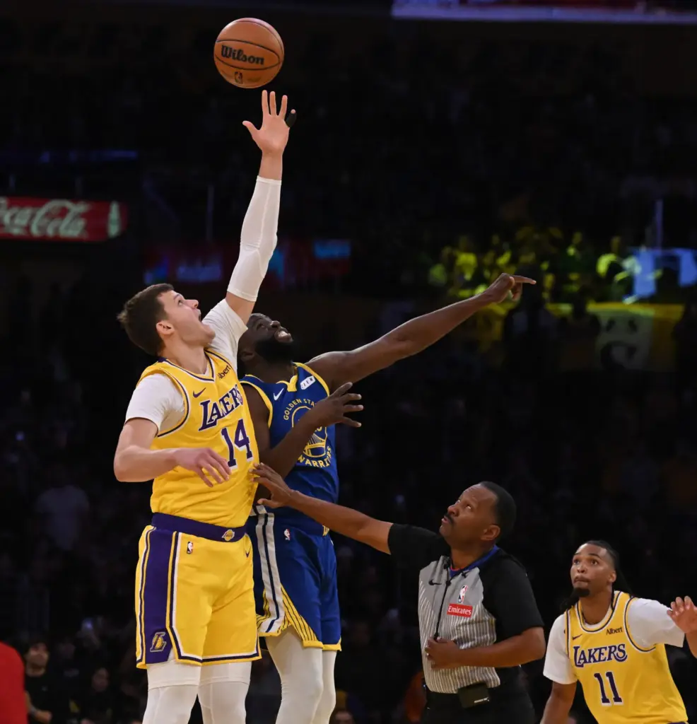 Lakers center Walker Kessler, left, wins the opening tip-off against...