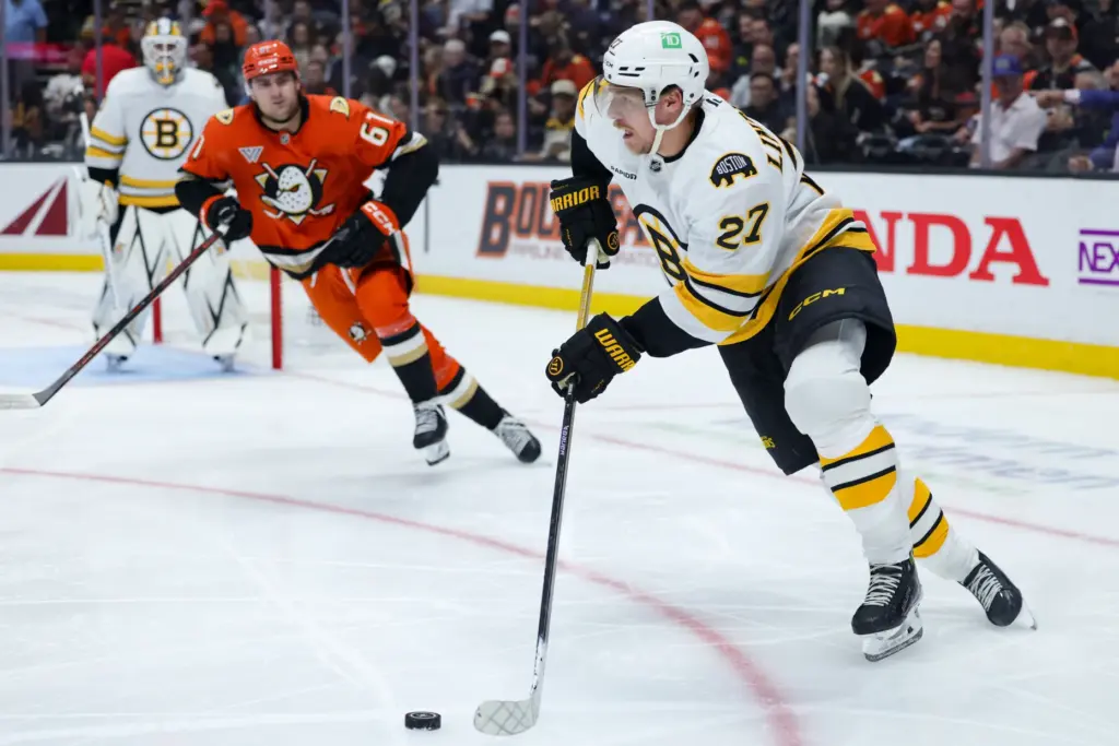 Boston Bruins defenseman Hampus Lindholm, right, moves the puck as...
