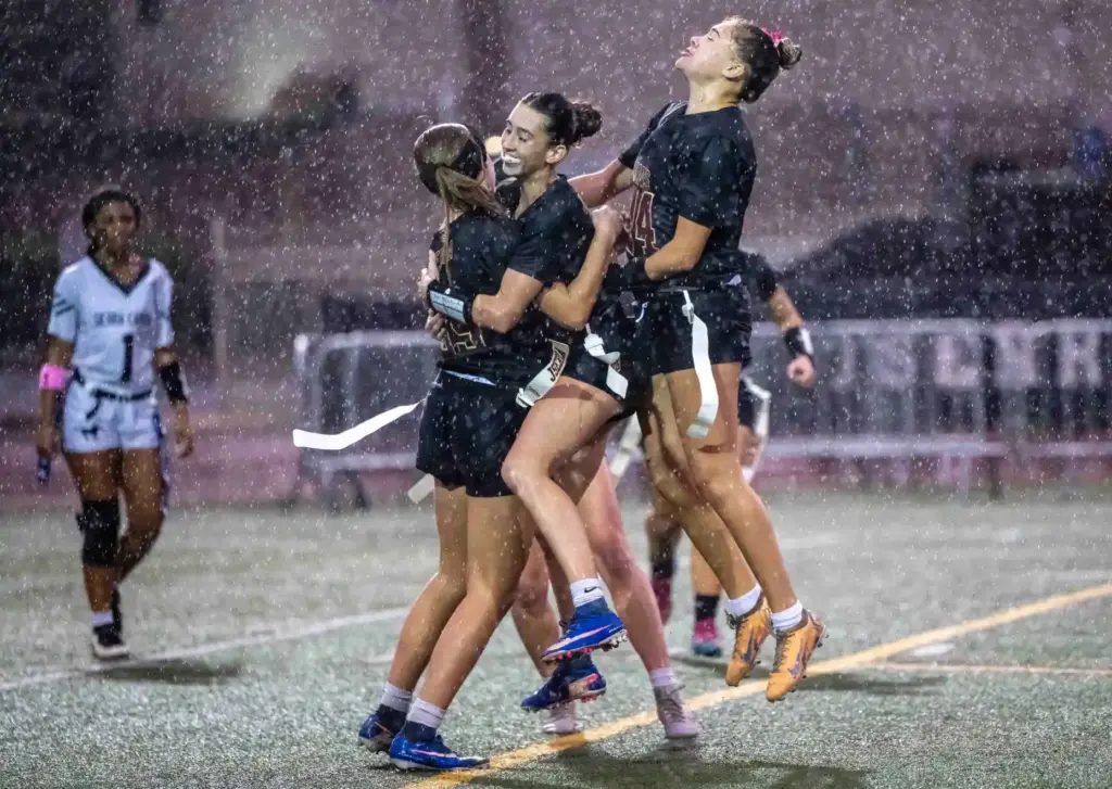 JSerra players celebrate a touchdown during a downpour of rain...