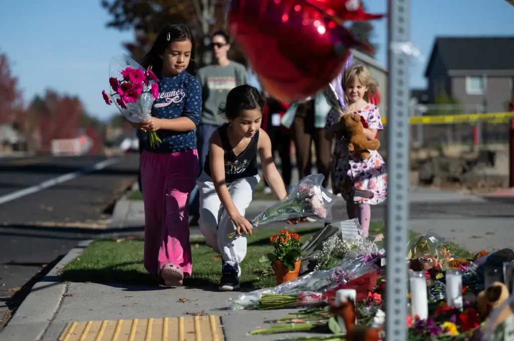 Children place flowers at a makeshift memorial outside Silver Rail...