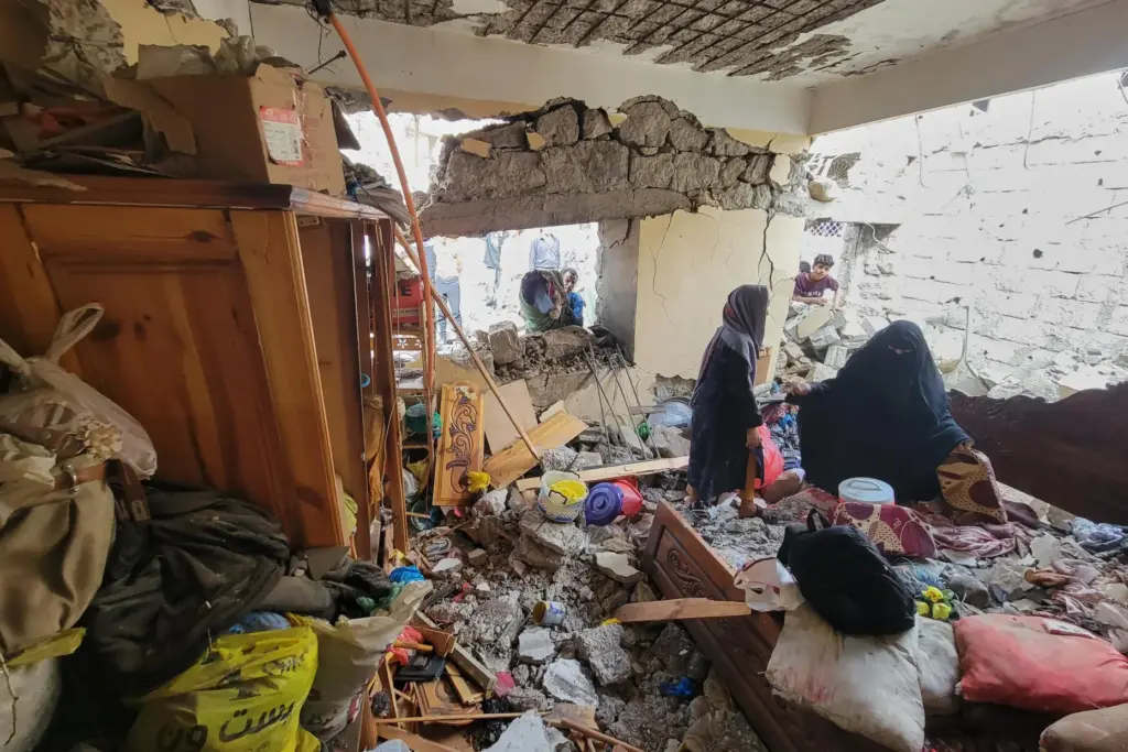 Residents walk on their home debris at Seina district in Taiz, Yemen.