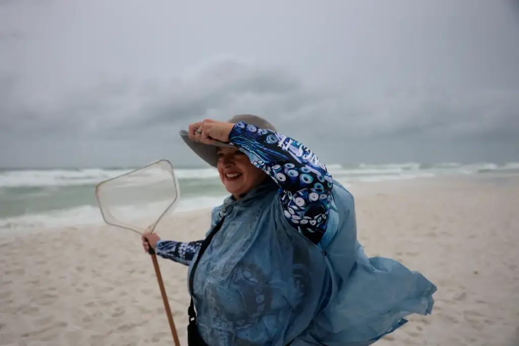 Jane Driscoll holds her hat as winds pick up while...