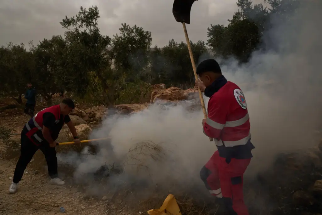 Palestinians extinguish a small fire after Israeli forces fired tear...