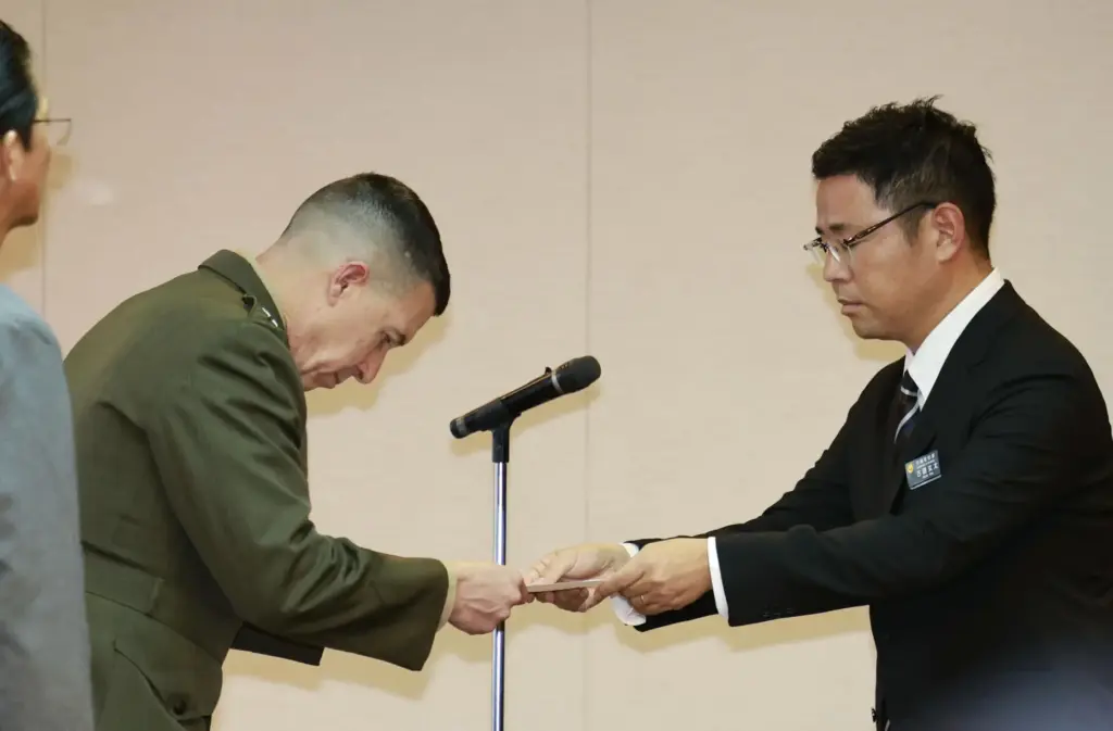 Okinawa Gov. Genta Koja hands a letter of protest to U.S. Marine Corps Lt. Gen. Benjamin T. Watson.