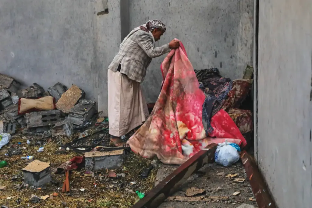 A man searches through the debris of his damaged home following airstrikes in Sanaa, Yemen.