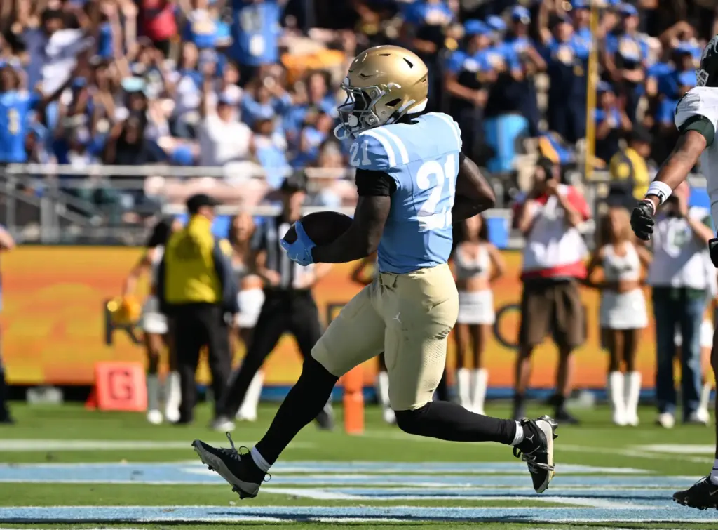 UCLA running back Jaivian Thomas (21) scores on a 7-yard...