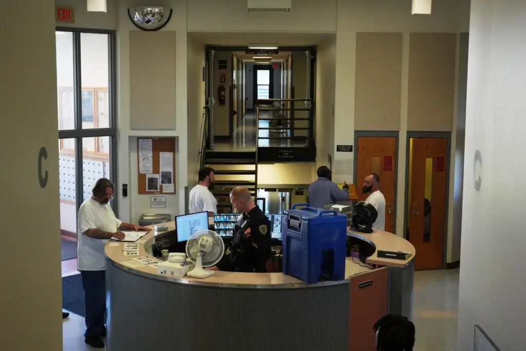 People who are incarcerated roam near the security desk, which...