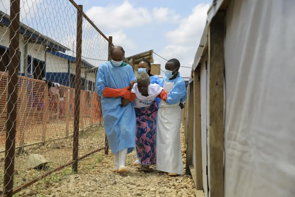 Healthcare workers help a patient who was cleared of Ebola...