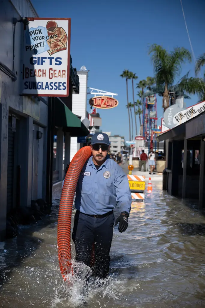 Newport Beach workers carry hoses and pumps to a flooded...