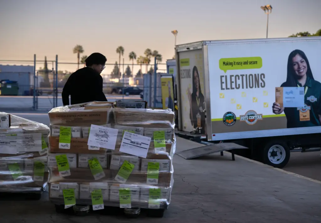 Election worker Oscar Garduno moves pallets of ballots from the...
