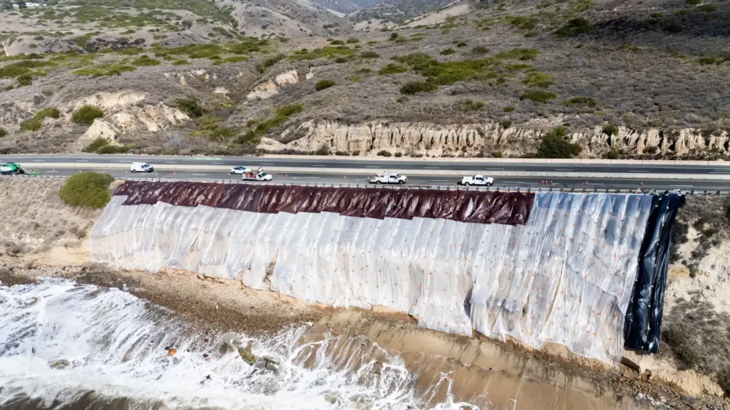 A tarp covers a crumbling bluff along Pacific Coast Highway...