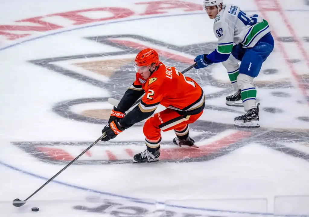 The Ducksâ Jackson LaCombe, left, controls the puck as the...