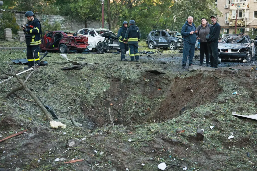 Local residents and emergency workers stand near a crater made by a Russian strike.