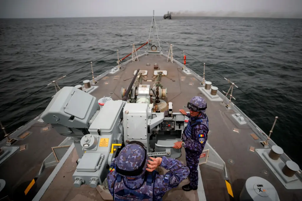 FILE – Romanian naval servicemen stand next to a gun...