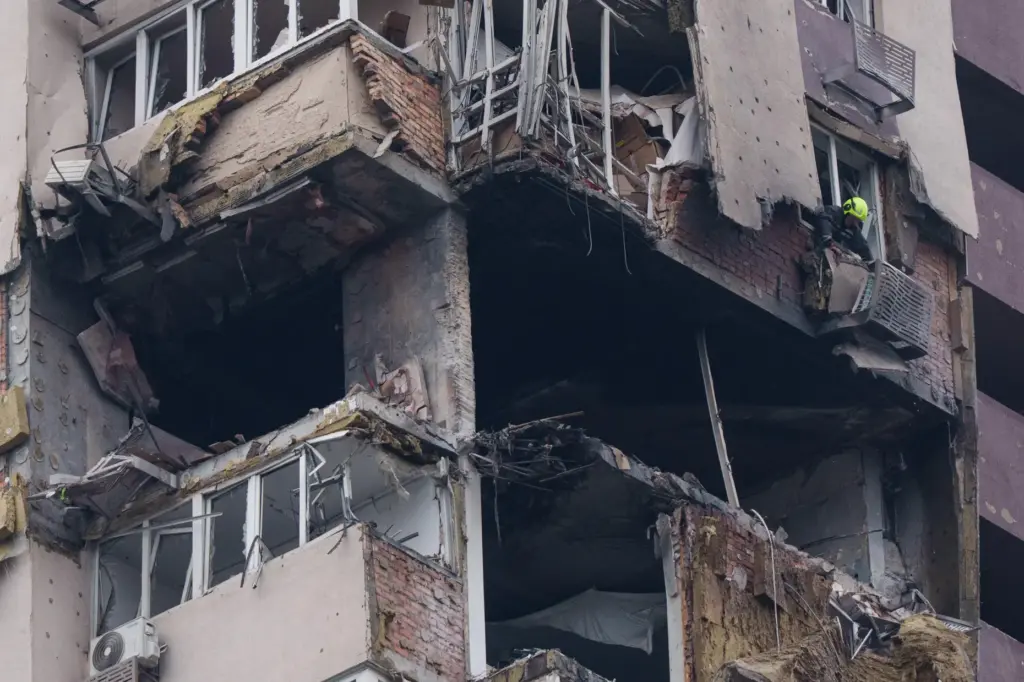 A rescue worker clears rubble from a multi-story residential building damaged in a Russian drone strike.