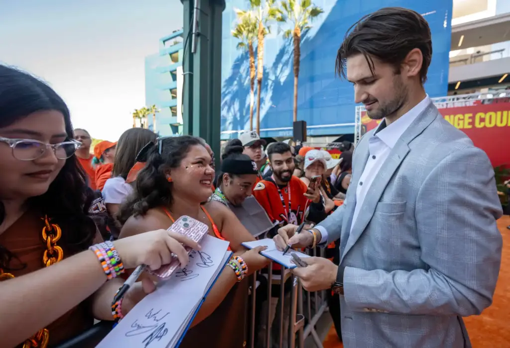 Ducks player Travis Mitchell signs autographs on the orange carpet...